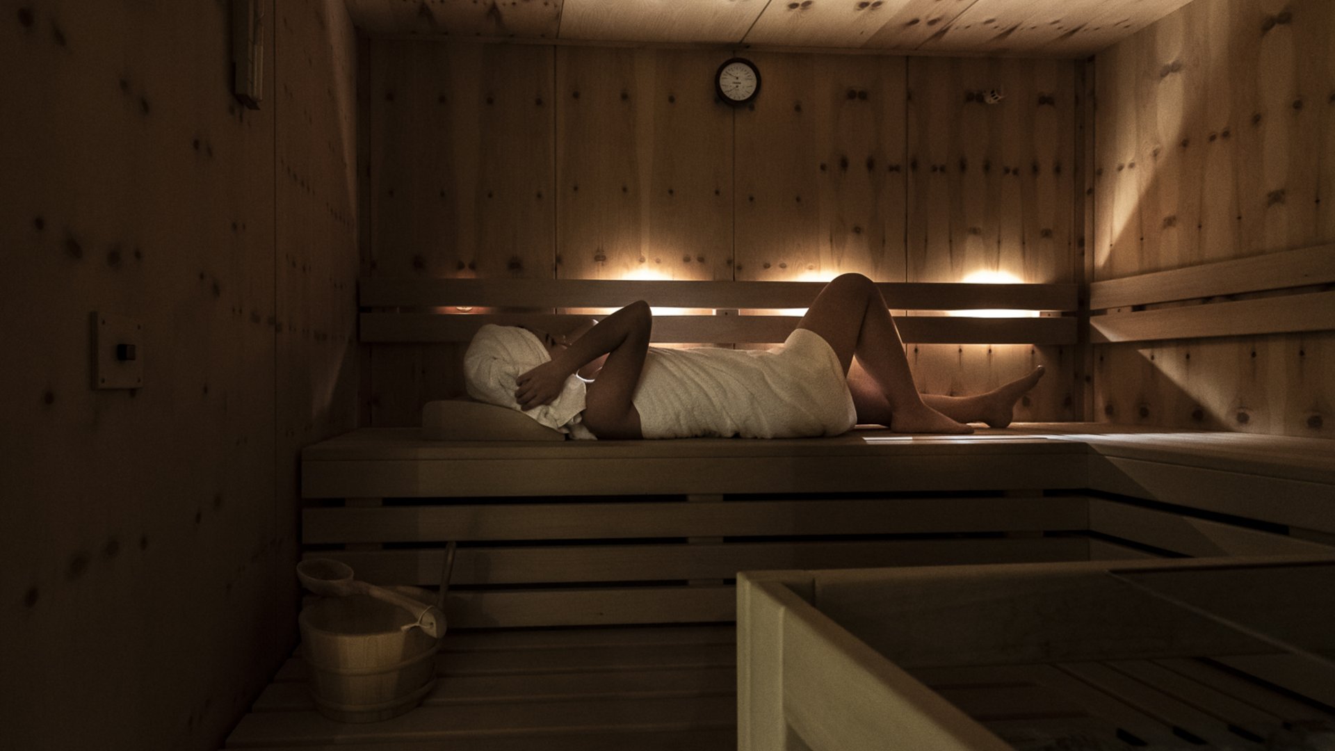 Person entspannt sich in Sauna, eingewickelt in Handtuch und Turban