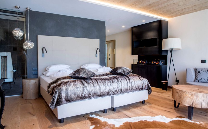 Modernes Schlafzimmer mit Doppelbett, Kamin und Holzmöbeln