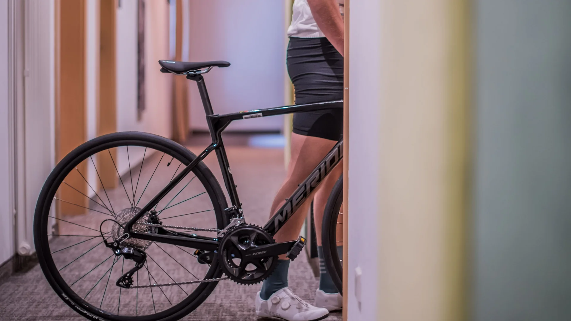 Schwarz Rennrad neben Person in Radbekleidung im Flur