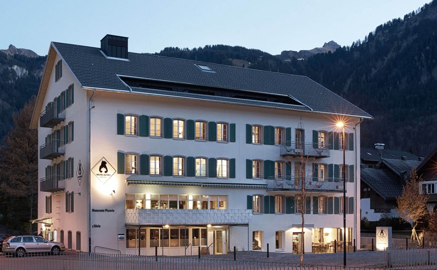 Illuminated hotel building with mountains in the background at dusk