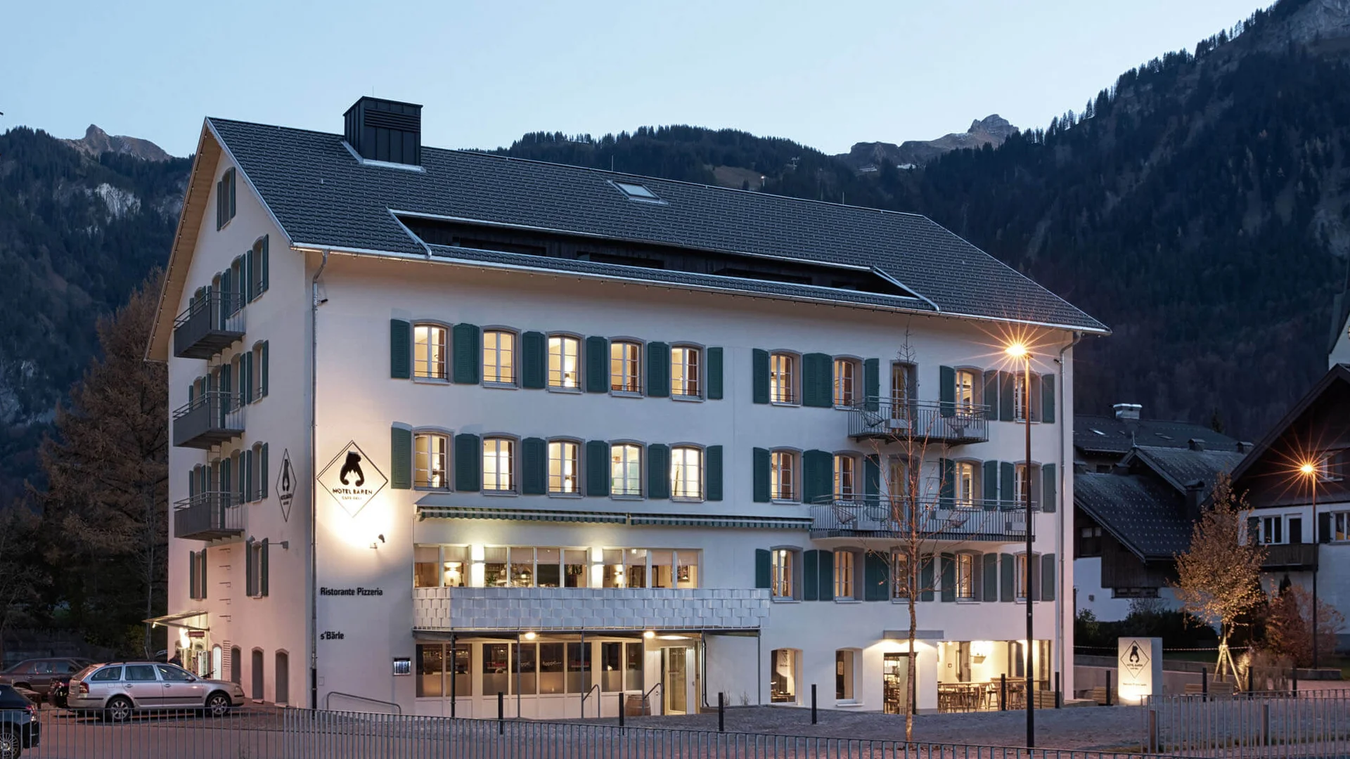Mit @lottipower auf Rennradurlaub im Bregenzerwald © Hotel Bären - Cafe Deli Mellau Beleuchtetes Hotelgebäude mit Bergen im Hintergrund bei Dämmerung