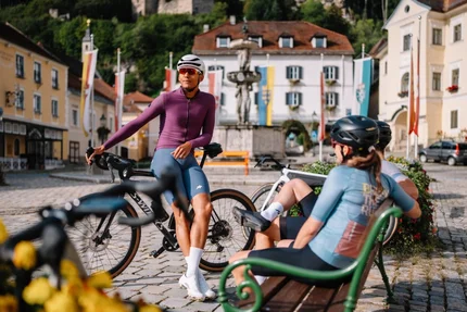 Radfahrer in Sportkleidung ruhen sich in historischem Stadtplatz aus