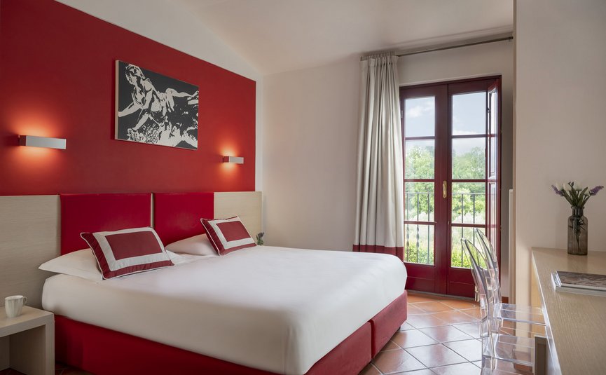 Hotel & Restaurant Casolare Le Terre Rosse ***S © Hotel Casolare Le Terre Rosse Modernes Schlafzimmer mit roter Wand und Balkonfenster
