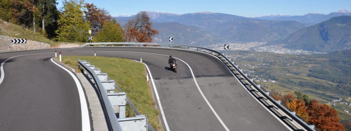 One week of motorcycling in the South of South Tyrol Winding mountain road with motorcyclist and valley and mountain view