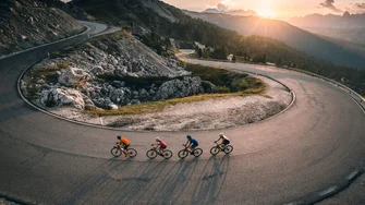Quattro ciclisti su una strada di montagna al tramonto