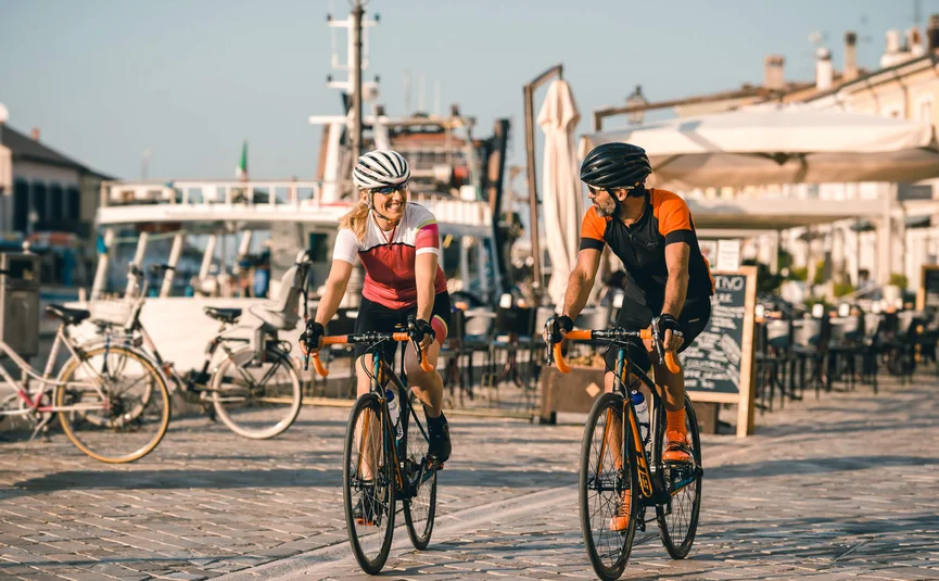 Vacanze in bici da corsa sulla costa adriatica © Alex Moling Due ciclisti, uomo e donna, pedalano su un sentiero lastricato vicino all'acqua