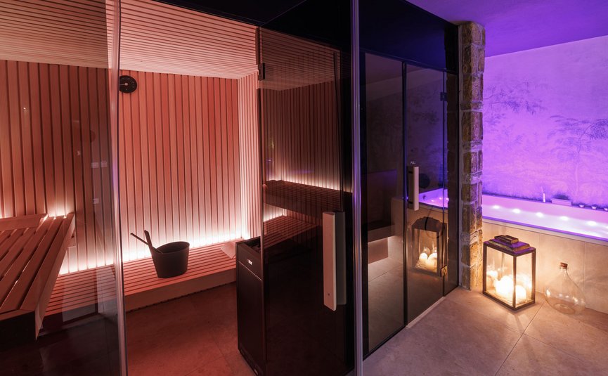 Sauna room with wooden interior and adjacent hot tub with candle lighting