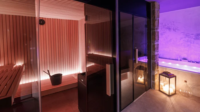 Area sauna con interno in legno e vasca idromassaggio adiacente con luci a candela
