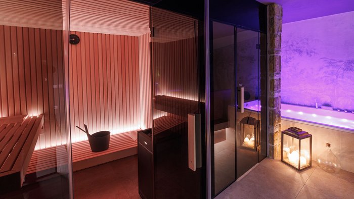Saunabereich mit Holzinterieur und angrenzendem Whirlpool mit Kerzenbeleuchtung