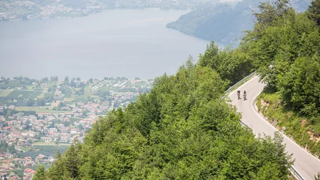 Die schönsten Rennrad-Regionen und Tipps für den Herbst © Heiko Mandl Zwei Radfahrer fahren bergauf auf kurviger Straße mit Seenblick