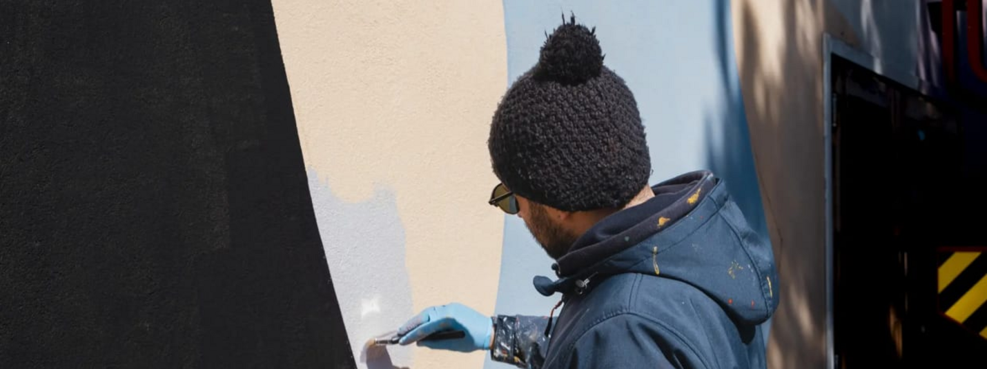 Frühling mit Ihrem vierbeinigen Freund Man met muts schildert muur met penseel en blauwe verf