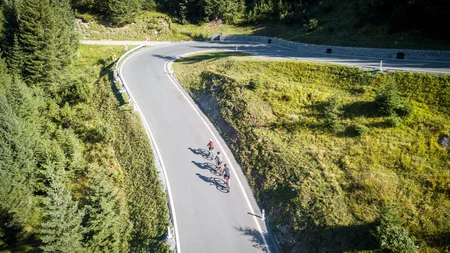 Tre ciclisti che percorrono una strada di montagna tortuosa