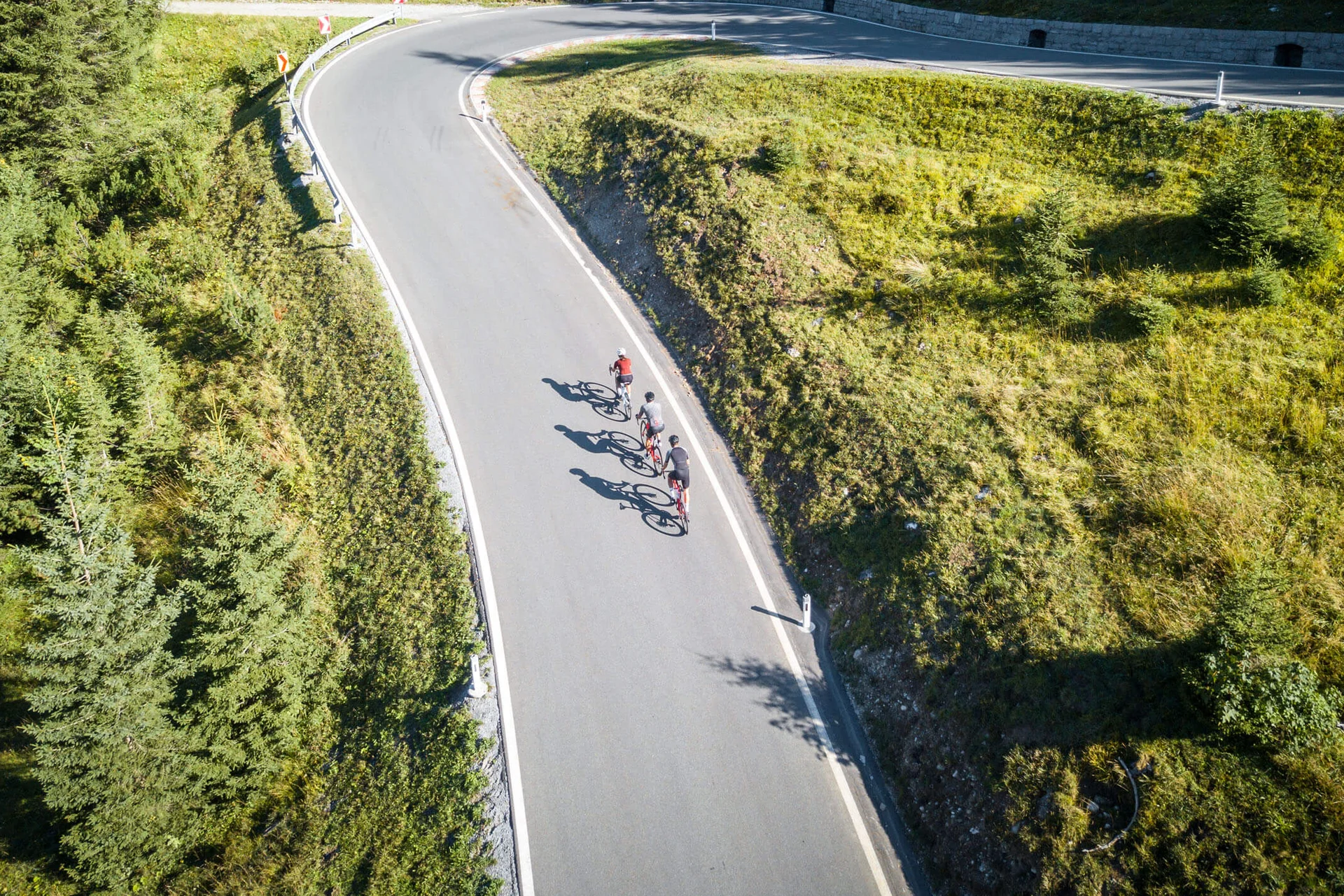 Drie fietsers op een kronkelende bergweg