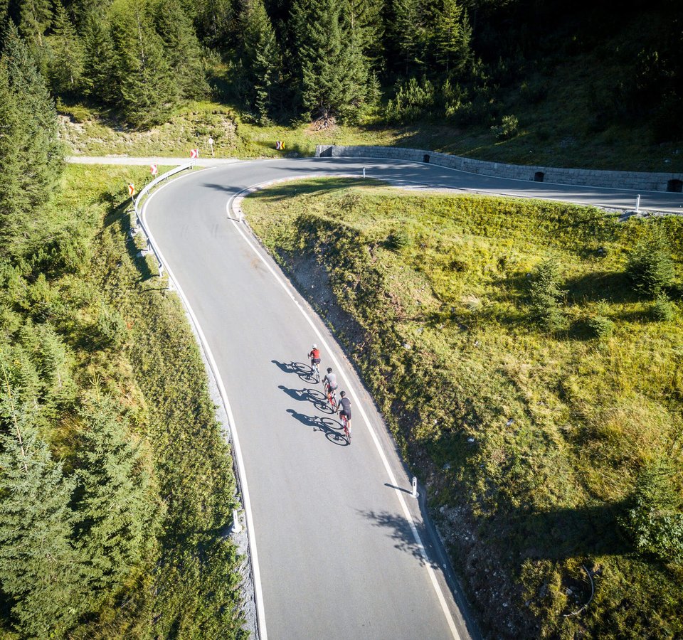 3 Highlights für deinen Rennradurlaub im Tannheimer Tal © Christina Neubauer Drei Radfahrer fahren eine kurvige Bergstraße entlang