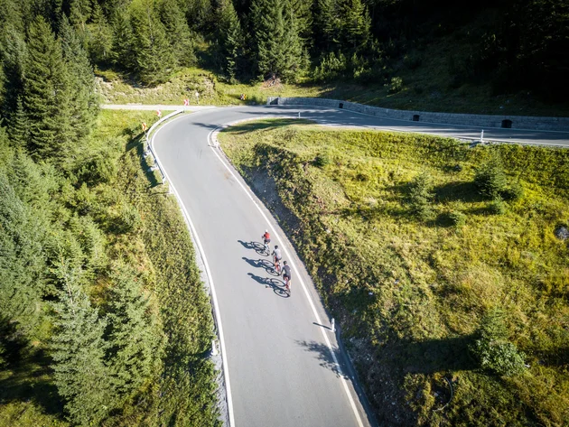 Tre ciclisti che percorrono una strada di montagna tortuosa
