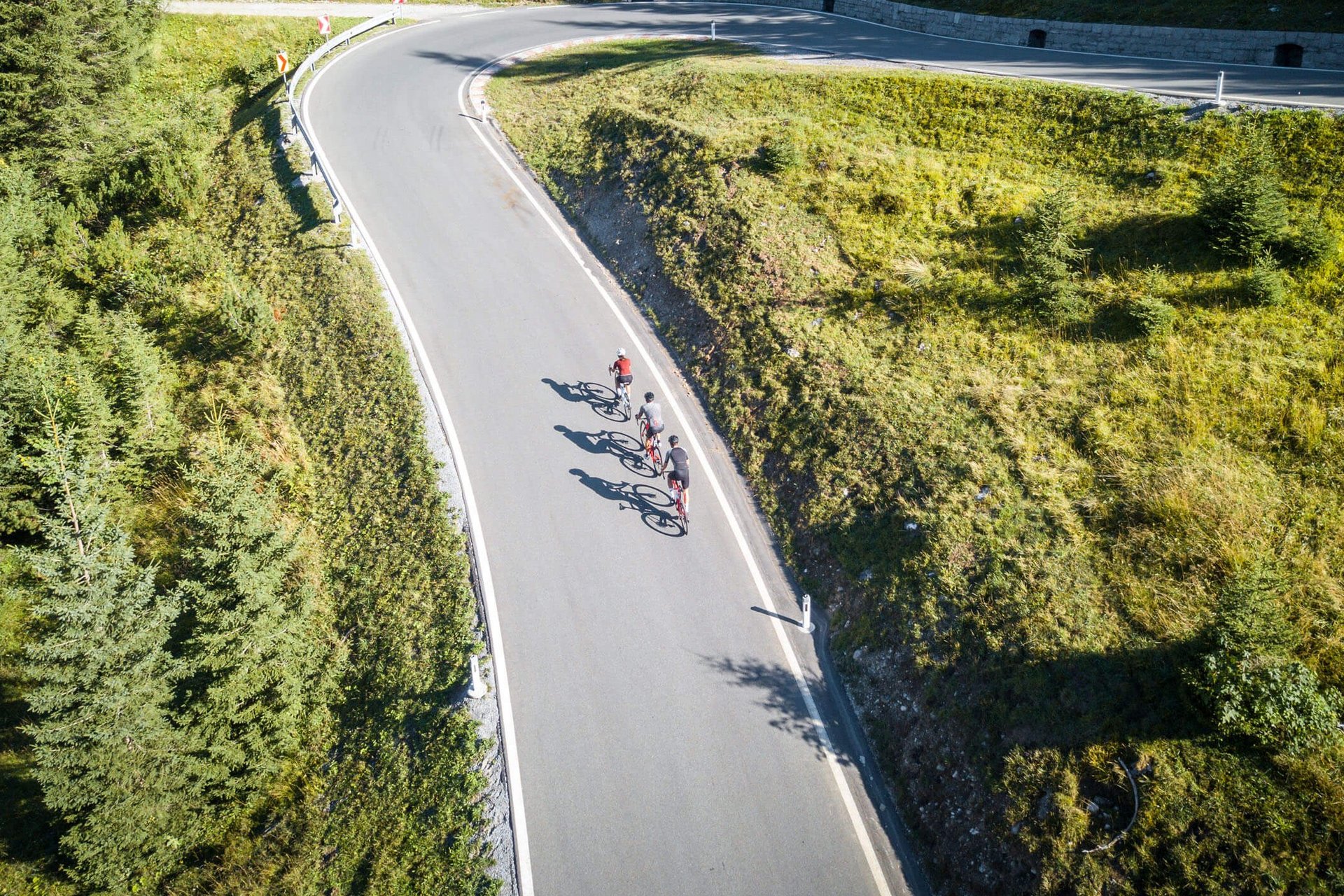 Roadbike Holidays © Christina Neubauer Drei Radfahrer fahren eine kurvige Bergstraße entlang