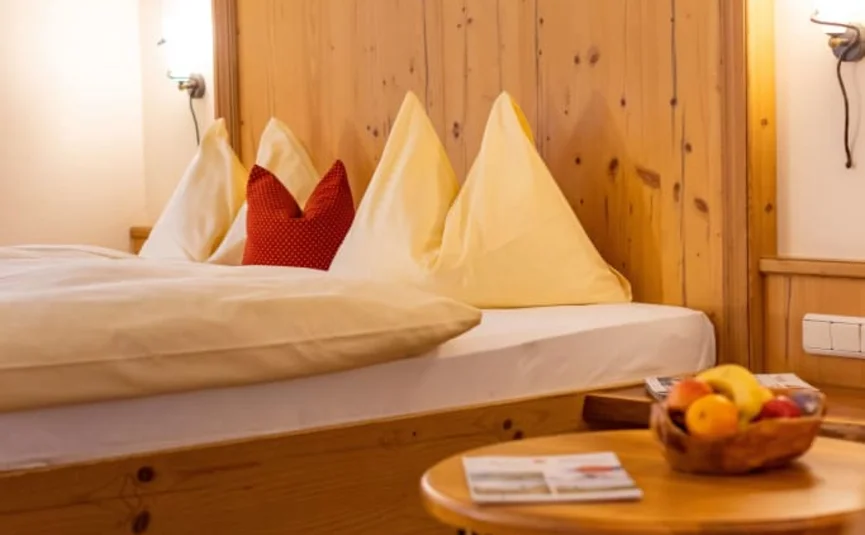 Comodo letto in legno con cuscini e cesta di frutta sul tavolo nella stanza