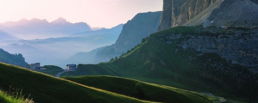 Grüne Hügel und Bergklippen bei Sonnenaufgang in den Alpen