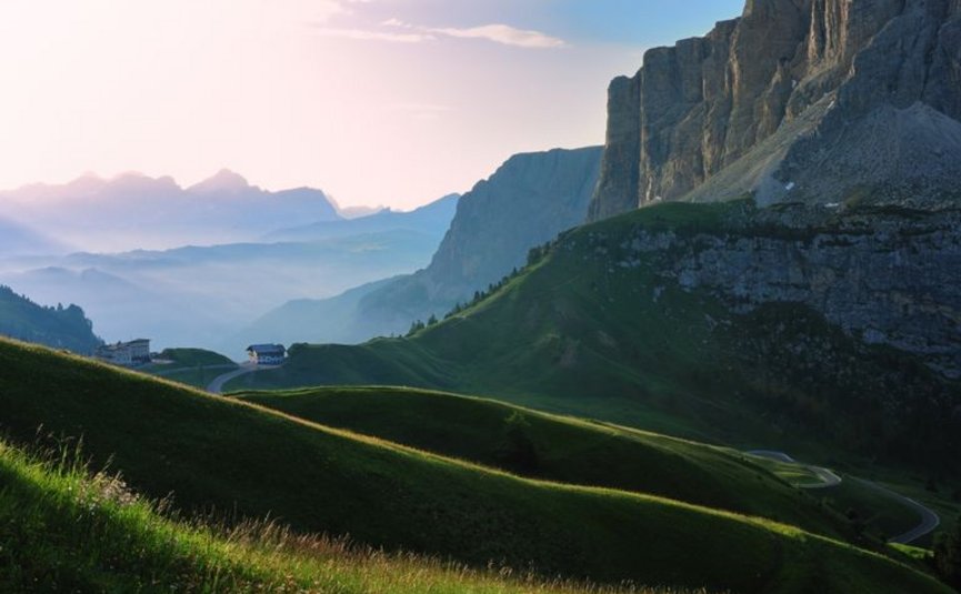 Colline verdi e scogliere montuose all'alba nelle Alpi