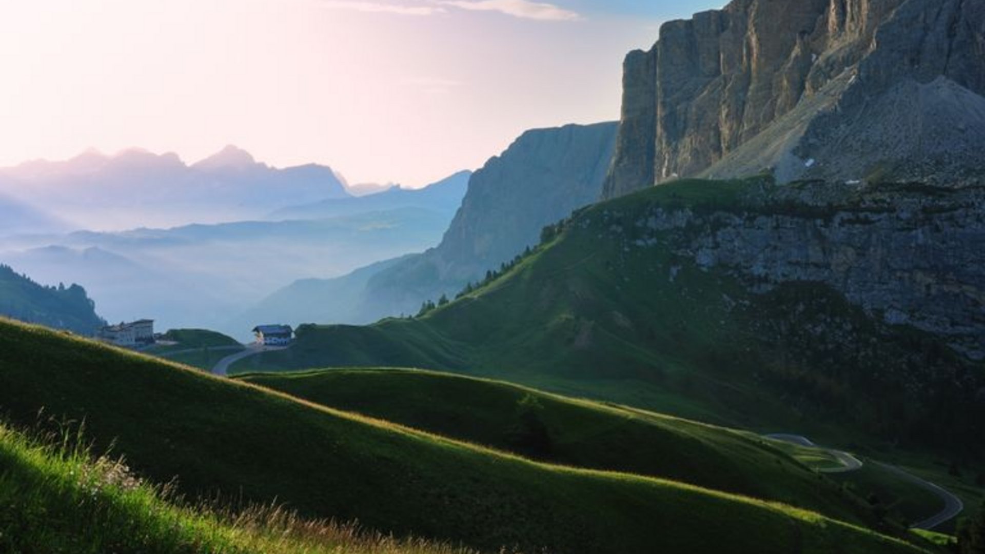 Grüne Hügel und Bergklippen bei Sonnenaufgang in den Alpen