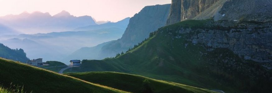 Grüne Hügel und Bergklippen bei Sonnenaufgang in den Alpen