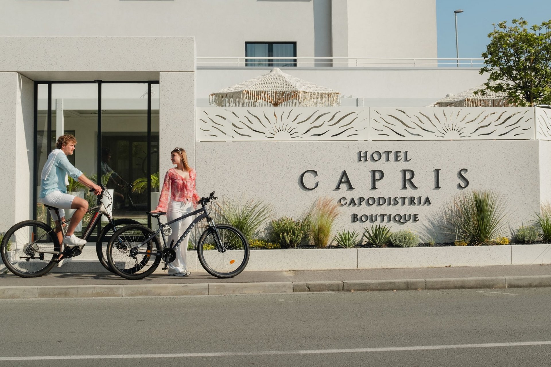 Man en vrouw met fietsen voor Hotel Capris