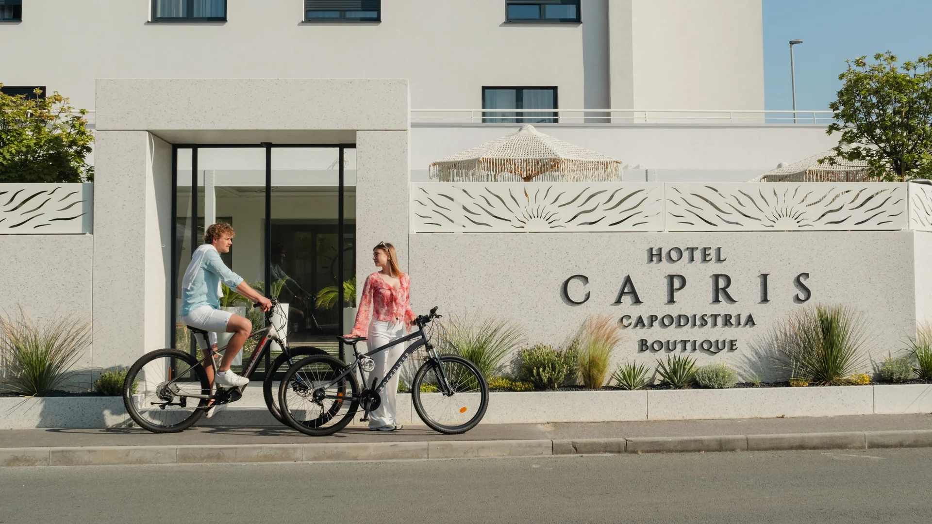 Man and woman with bicycles in front of Hotel Capris