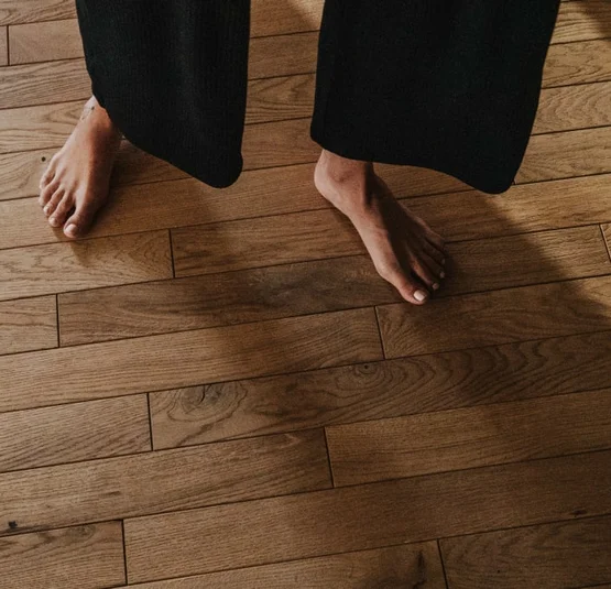 Persona a piedi nudi su pavimento in parquet di legno