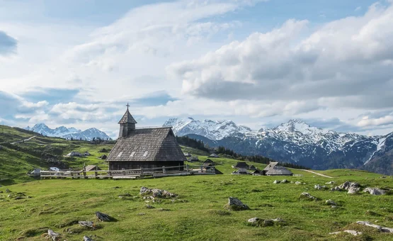 Rennrad Urlaub im Savinja Tal © Matic Gobec Holzkirche auf grüner Alm mit schneebedeckten Bergen im Hintergrund