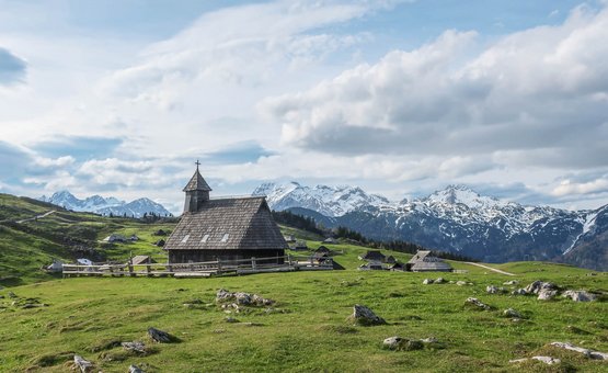 Chiesa di legno su prato verde con montagne innevate sullo sfondo