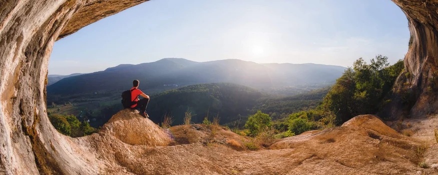 Breeze, Pulse oder Peak? 20 neue Traumrouten im Slowenischen Istrien © Jaka Ivancic Person sitzt in einer Höhle und blickt auf sonnige Berglandschaft
