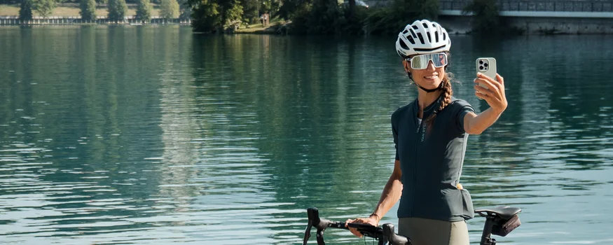 Breeze, Pulse oder Peak? 20 neue Traumrouten im Slowenischen Istrien © Alain Rumpf Frau mit Fahrrad macht Selfie am See mit Berg und Schloss im Hintergrund