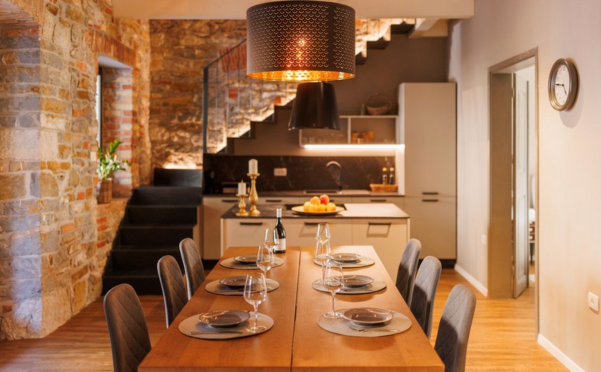 Modern dining area with wooden table, stylish chairs, and open kitchen in the background