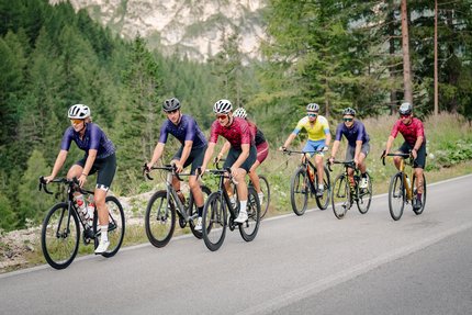 Gruppe von Radfahrern auf einer Bergstraße umgeben von Bäumen