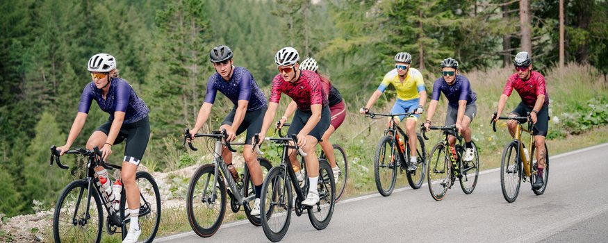 Gruppo di ciclisti su strada di montagna circondata da alberi