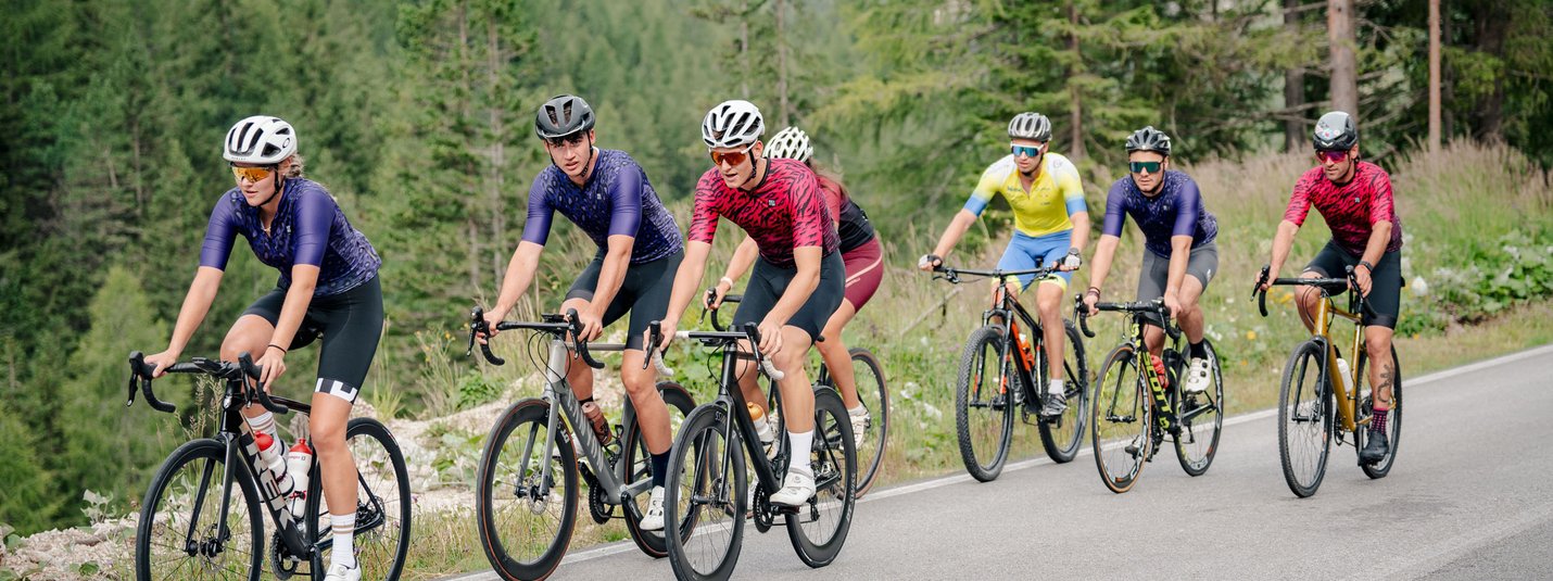 Gruppo di ciclisti su strada di montagna circondata da alberi