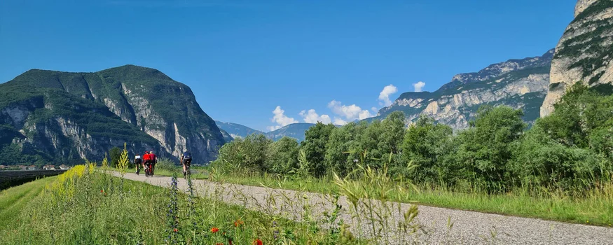 Cyclists on path with mountains and blue sky in background
