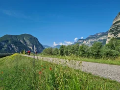 Cyclists on path with mountains and blue sky in background