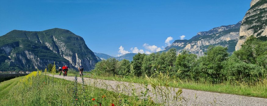 Radfahrer auf Weg mit Bergen und blauem Himmel im Hintergrund