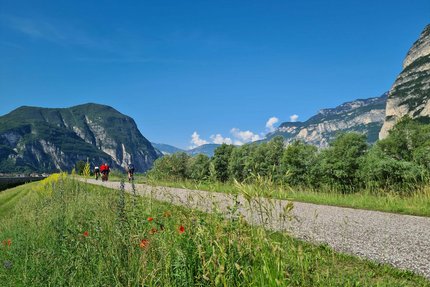 Cyclists on path with mountains and blue sky in background