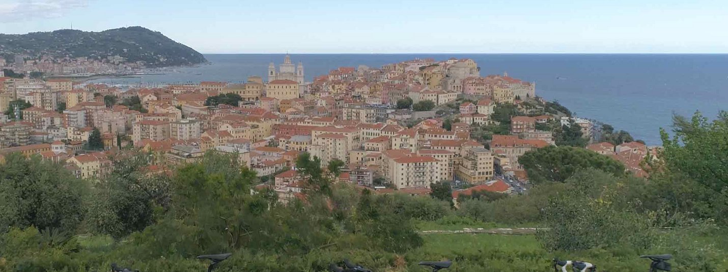 Bandiere Arancioni: tot Dolceacqua © Villa Giada spEace & Bike Resort Drie rode racefietsen met uitzicht op een kuststad onder een blauwe lucht