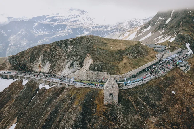 Roadbike Holidays © BRUCK FUSCH GROSSGLOCKNER JFK Photography Menschen auf einer Bergstraße mit schneebedeckten Gipfeln im Hintergrund
