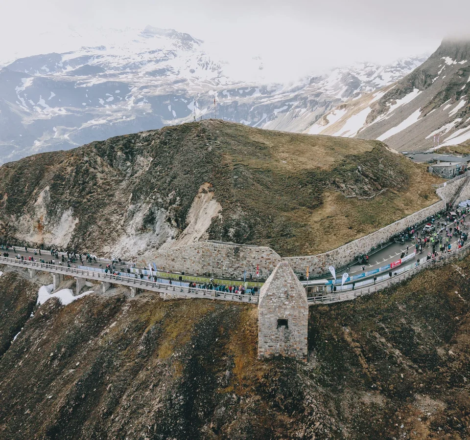 Glocknerkönig 2026 © BRUCK FUSCH GROSSGLOCKNER JFK Photography Menschen auf einer Bergstraße mit schneebedeckten Gipfeln im Hintergrund