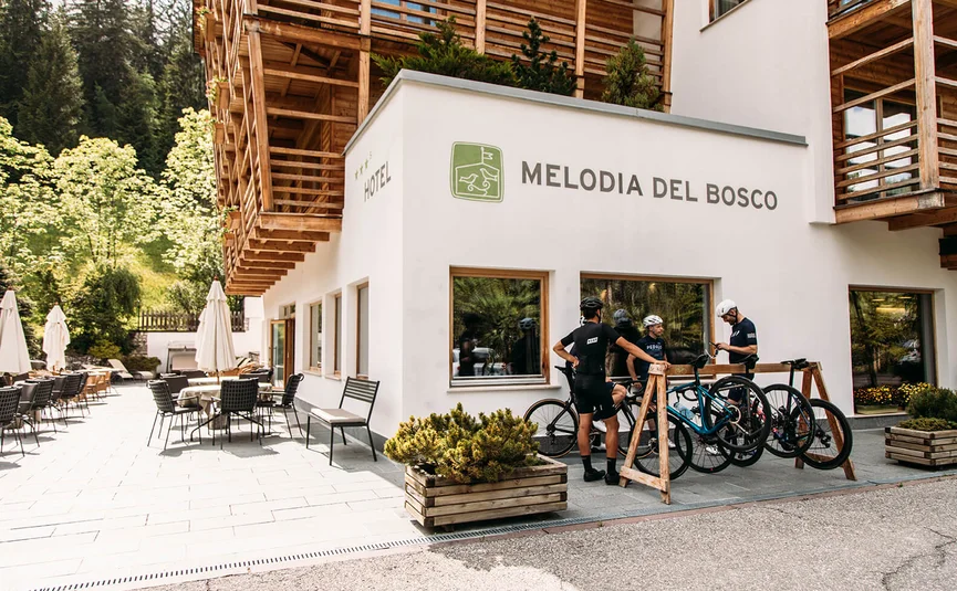 Ciclisti fuori dall'hotel Melodia del Bosco con balconi in legno