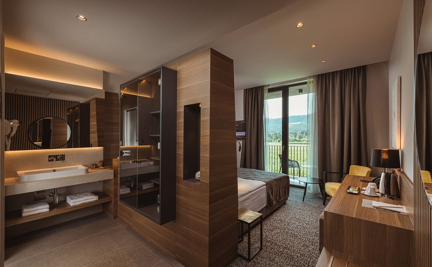 Camera d'hotel moderna con bagno integrato e balcone con vista sulle montagne