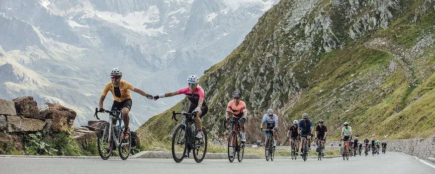 Cyclists riding in mountains, two holding hands
