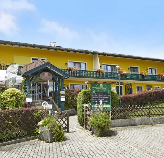 Gelbes Landhotel mit Balkon und Garten im sonnigen Tag