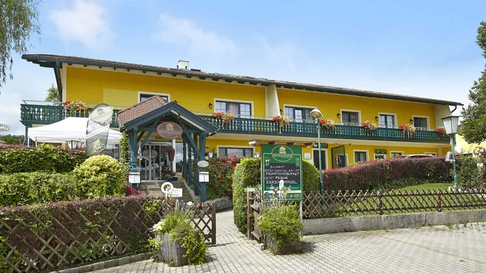 Gelbes Landhotel mit Balkon und Garten im sonnigen Tag