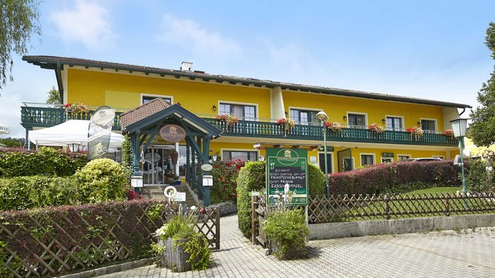 Gelbes Landhotel mit Balkon und Garten im sonnigen Tag
