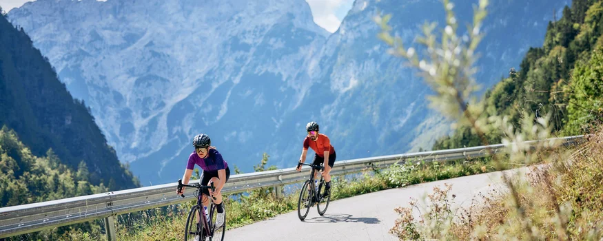 Breeze, Pulse oder Peak? 20 neue Traumrouten im Slowenischen Istrien © Tobias Köhler Zwei Radfahrer fahren auf bergiger Straße mit Alpen im Hintergrund